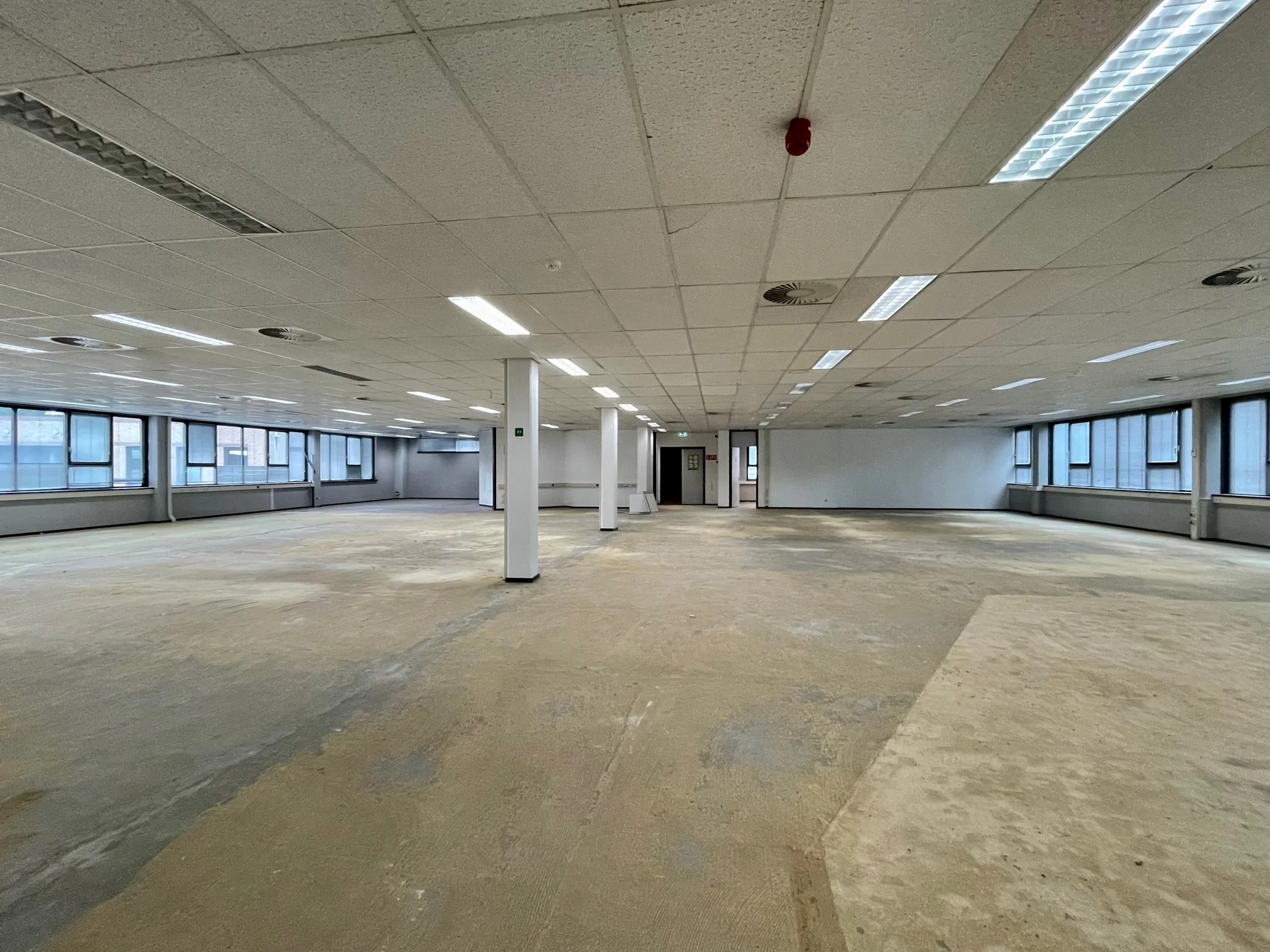 Leegstaand kantoorpand aan de Rivium 4e Straat met systeemplafond, pilaren en grote ramen.